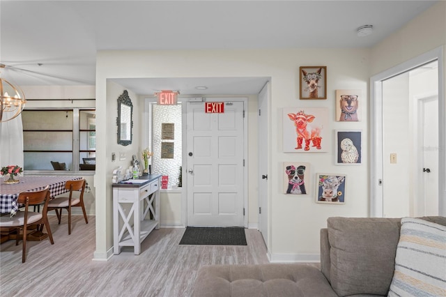 entryway featuring light wood-style floors, baseboards, and an inviting chandelier