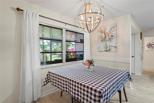 dining area featuring baseboards, light wood finished floors, and an inviting chandelier