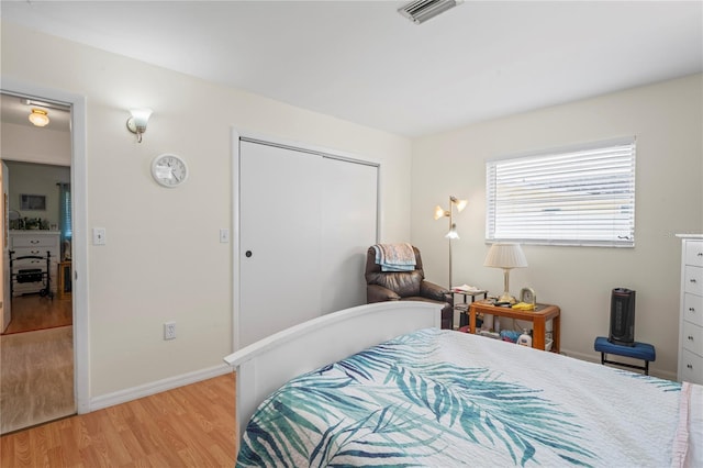 bedroom featuring light wood-type flooring, a closet, visible vents, and baseboards