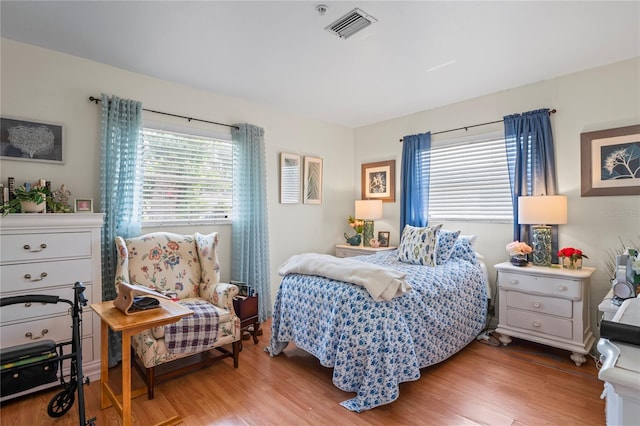 bedroom featuring light wood-style flooring, multiple windows, and visible vents