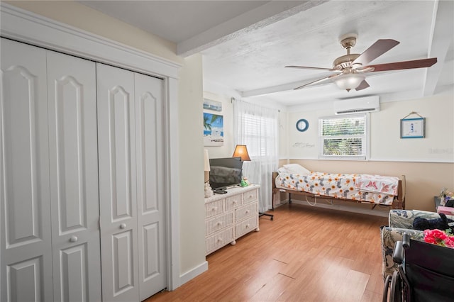 bedroom featuring a closet, a wall mounted air conditioner, beam ceiling, and light wood-style floors