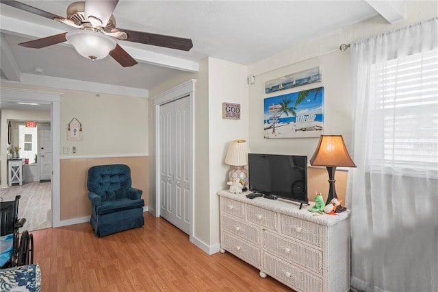 sitting room featuring a wainscoted wall, a ceiling fan, and light wood-style floors