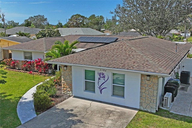 view of front of home featuring stone siding, stucco siding, a front lawn, and roof with shingles