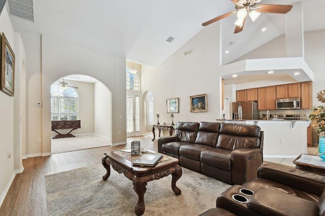 living room featuring high vaulted ceiling, light hardwood / wood-style floors, and ceiling fan