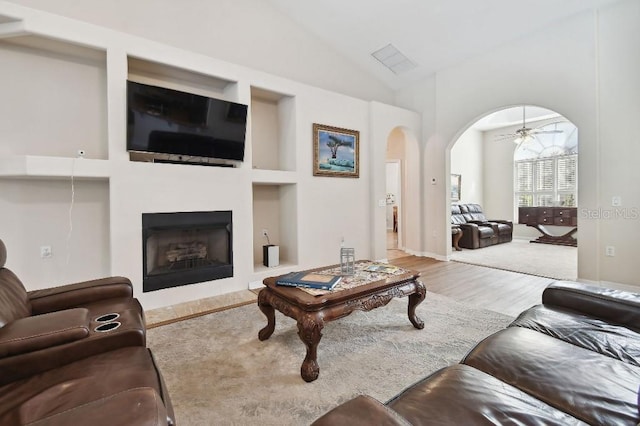 living room featuring ceiling fan, lofted ceiling, and wood-type flooring