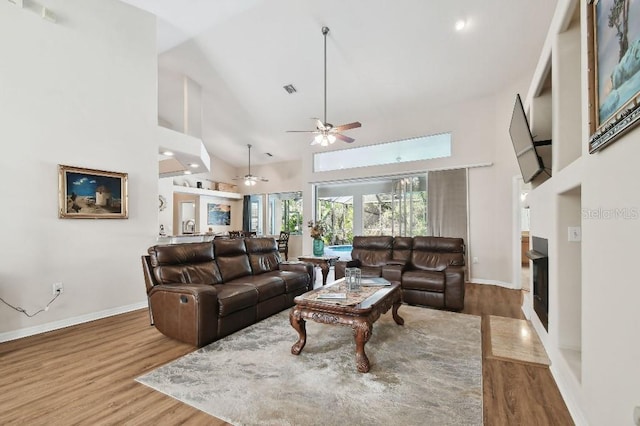 living room with ceiling fan, wood-type flooring, and high vaulted ceiling