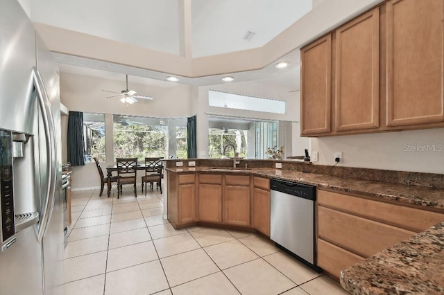 kitchen featuring appliances with stainless steel finishes, sink, dark stone counters, light tile patterned floors, and ceiling fan