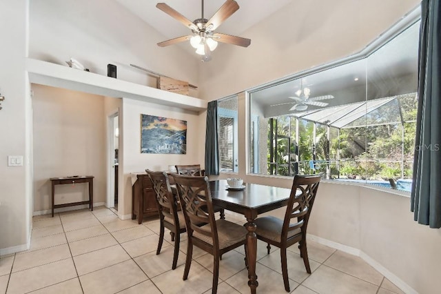 dining space with ceiling fan, a high ceiling, and light tile patterned floors