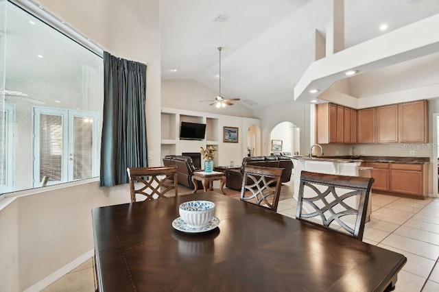 dining space with light tile patterned floors, high vaulted ceiling, sink, and ceiling fan