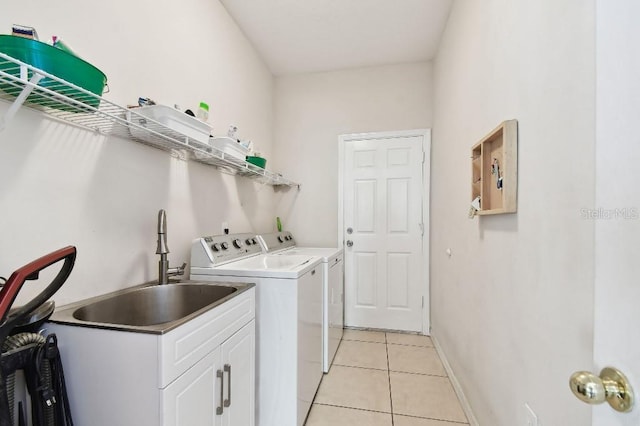 laundry room featuring light tile patterned floors, cabinets, sink, and washing machine and clothes dryer