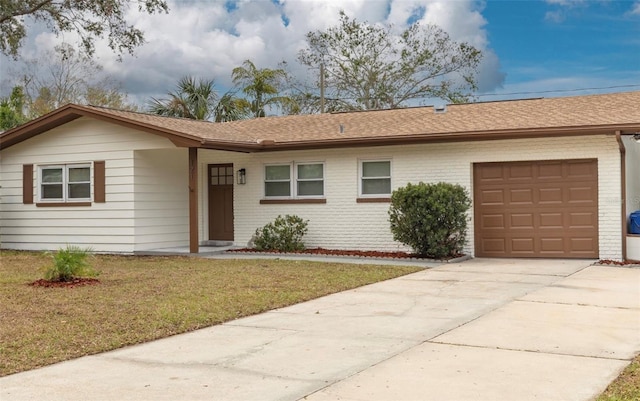 ranch-style home with brick siding, a shingled roof, concrete driveway, a front yard, and an attached garage