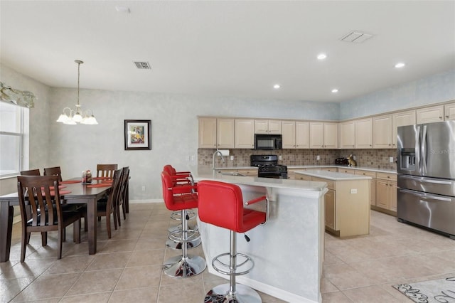 kitchen featuring light tile patterned floors, a center island, decorative light fixtures, black appliances, and a breakfast bar area