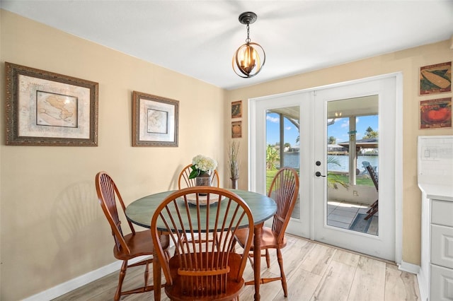 dining room with light hardwood / wood-style flooring, french doors, and a water view