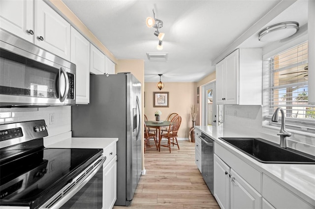 kitchen featuring sink, backsplash, stainless steel appliances, light hardwood / wood-style floors, and white cabinets