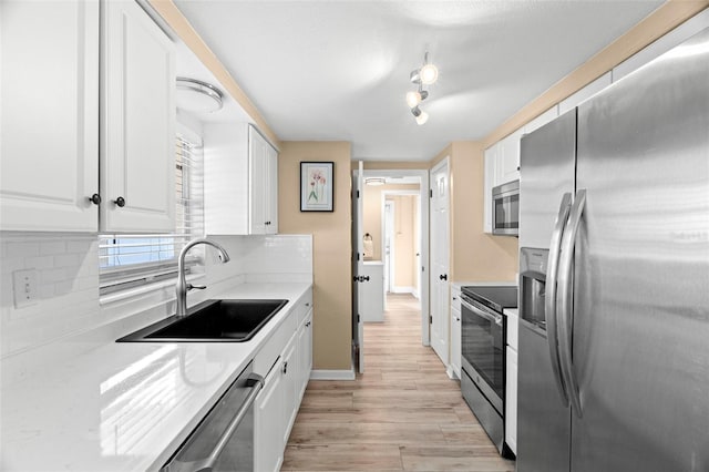 kitchen with white cabinetry, appliances with stainless steel finishes, sink, and backsplash