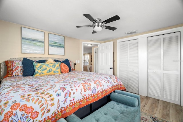 bedroom with hardwood / wood-style flooring, two closets, and ceiling fan