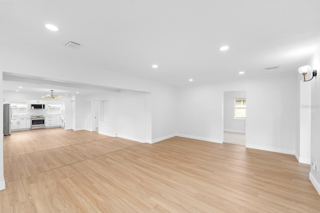 unfurnished living room with light hardwood / wood-style flooring and a notable chandelier