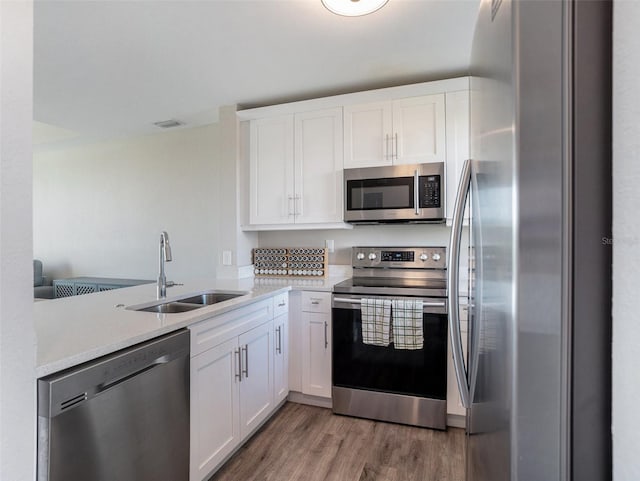 kitchen with appliances with stainless steel finishes, white cabinetry, sink, kitchen peninsula, and dark wood-type flooring