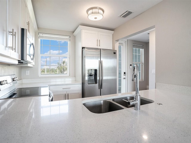 kitchen featuring white cabinetry, sink, stainless steel appliances, and light stone countertops
