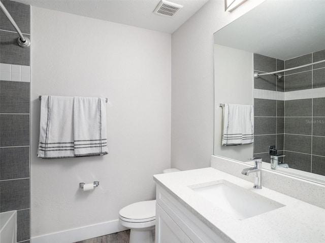 bathroom featuring vanity, wood-type flooring, tiled shower, and toilet
