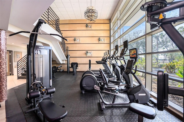 gym featuring floor to ceiling windows, plenty of natural light, and wooden walls