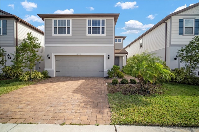 view of front of home with an attached garage, stucco siding, decorative driveway, and a front yard