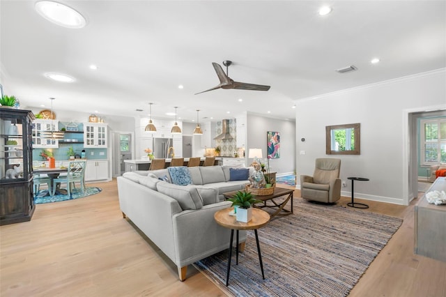 living room featuring ornamental molding, ceiling fan, and light hardwood / wood-style flooring