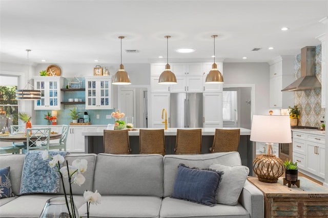 kitchen with wall chimney range hood, stainless steel refrigerator, and decorative light fixtures