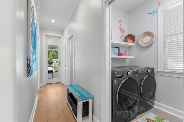 clothes washing area with crown molding, washer and dryer, and light hardwood / wood-style flooring