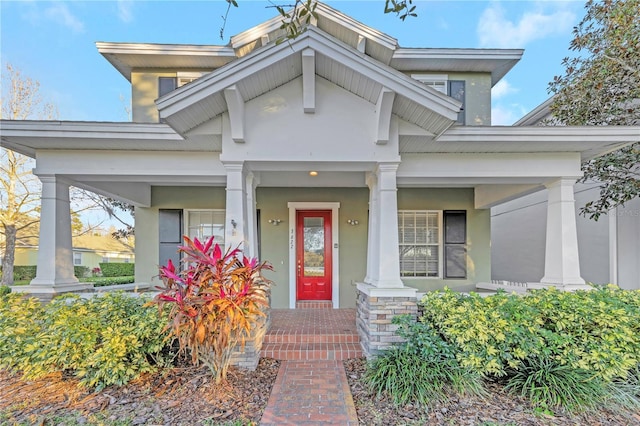 view of exterior entry featuring covered porch and stucco siding