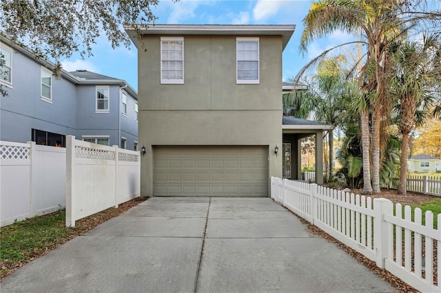 view of front of house with a fenced front yard, driveway, an attached garage, and stucco siding