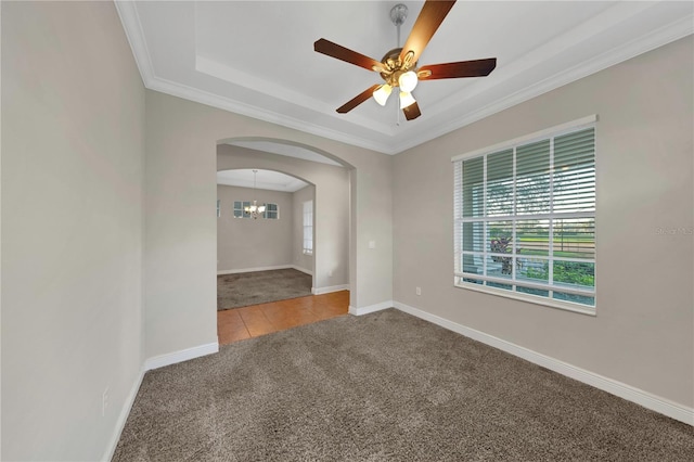 carpeted empty room with arched walkways, ornamental molding, ceiling fan with notable chandelier, and baseboards