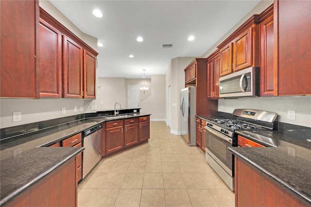 kitchen featuring decorative light fixtures, visible vents, appliances with stainless steel finishes, a sink, and dark brown cabinets