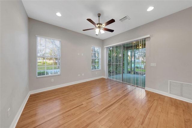 unfurnished room with a ceiling fan, light wood-type flooring, visible vents, and baseboards