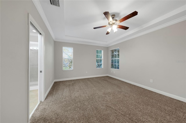 unfurnished room with visible vents, baseboards, ornamental molding, a tray ceiling, and carpet