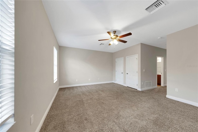 spare room with carpet floors, visible vents, and baseboards