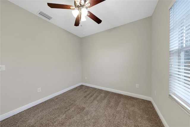 carpeted empty room with baseboards, visible vents, and a ceiling fan