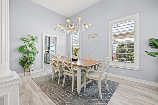 dining area with light wood-type flooring, an inviting chandelier, and baseboards