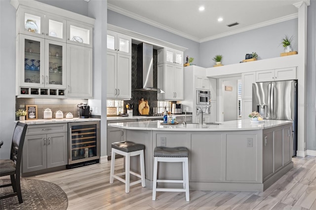 kitchen with wine cooler, crown molding, tasteful backsplash, a sink, and wall chimney exhaust hood