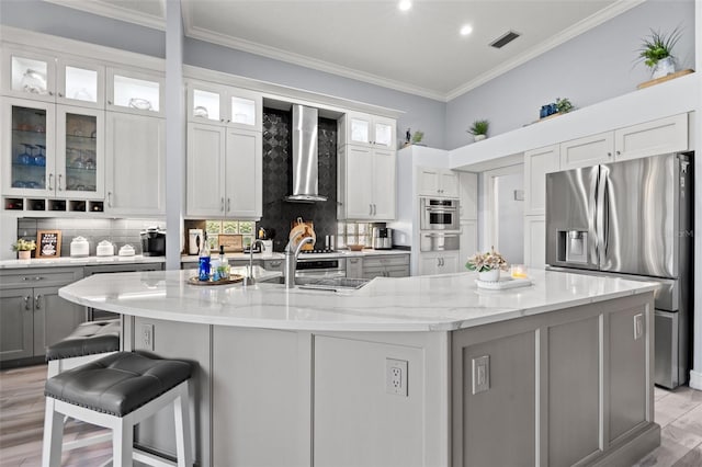 kitchen featuring visible vents, a large island, stainless steel appliances, crown molding, and wall chimney range hood