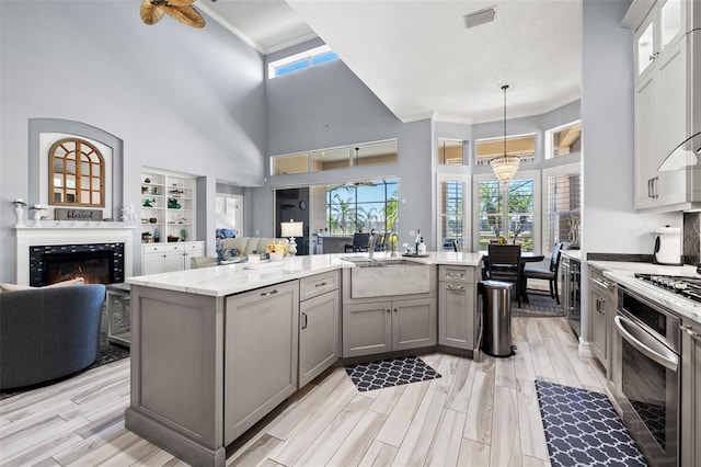 kitchen featuring oven, a sink, open floor plan, gray cabinets, and wood tiled floor