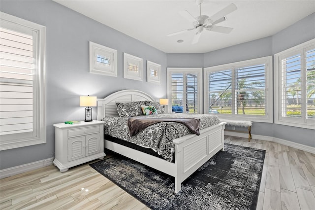 bedroom featuring light wood finished floors, a ceiling fan, and baseboards