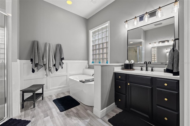 bathroom featuring a wainscoted wall, a bathing tub, a stall shower, vanity, and wood finished floors