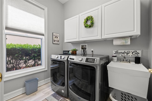 washroom featuring cabinet space, light wood-style floors, a sink, separate washer and dryer, and baseboards