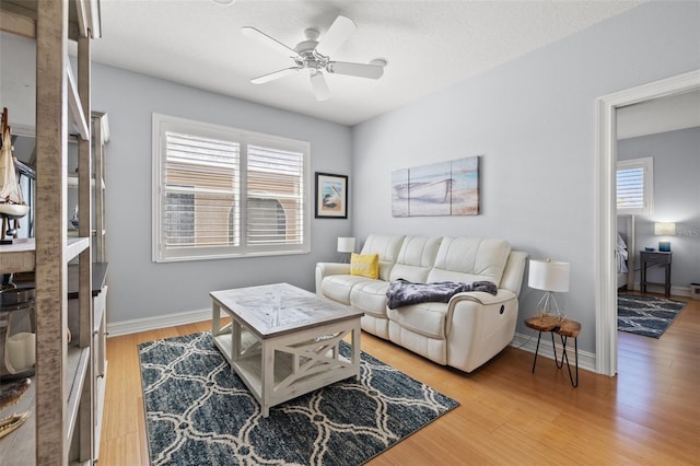 living area featuring ceiling fan, wood finished floors, a wealth of natural light, and baseboards