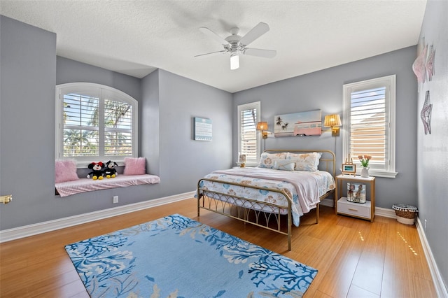 bedroom featuring multiple windows, wood finished floors, and baseboards