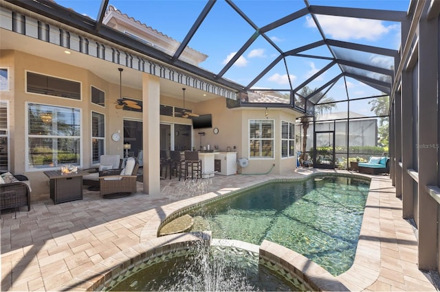 view of pool with an outdoor living space with a fire pit, outdoor dry bar, a pool with connected hot tub, a patio area, and a lanai