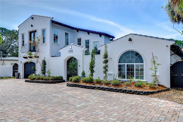 mediterranean / spanish-style house with driveway, a balcony, and stucco siding