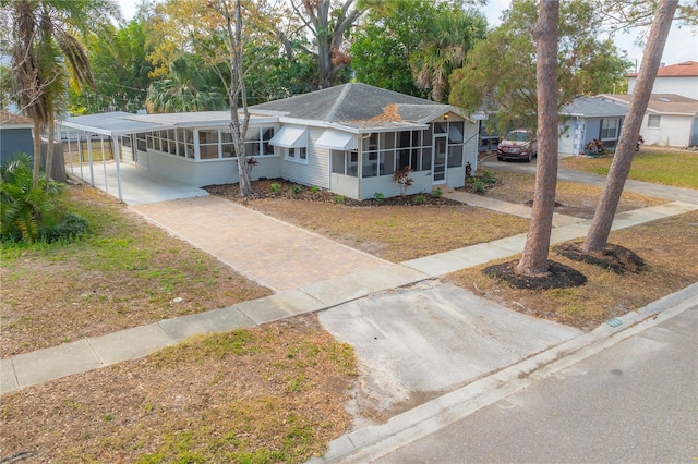 ranch-style home with a front lawn, a carport, and a sunroom