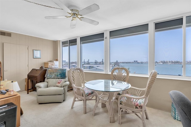 sunroom with a water view, ceiling fan, and a wealth of natural light